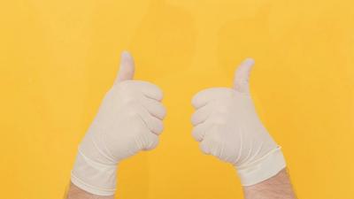 Latex-gloved hands give the thumbs up