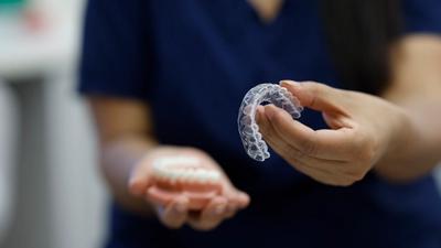 An orthodontist holds out Invisalign braces towards the camera